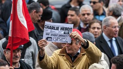 A Tunis, le 9 janvier 2015, un homme tient un vieux numéro de Charlie Hebdo pendant une manifestation de solidarité avec deux journalistes tunisiens, Nadhir Ktari et Sofiane Chourabi, disparus en Libye en septembre. (AFP - Anadolu Agency - Amine Landoulsi)