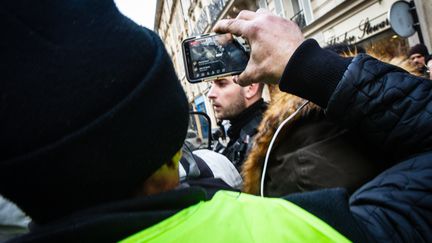 Un manifestant filme un officier de police avec son smartphone pendant une manifestation des "Gilets jaunes",&nbsp; le 14 décembre 2019 (AMAURY CORNU / HANS LUCAS)