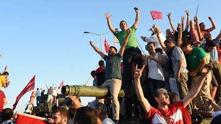 Ils ont répondu à l'appel du président. Comme ici sur le pont du Bosphore à Istanbul, des dizaines de milliers de personnes ont bravé les rebelles en grimpant sur les chars, déployés dans les rues. Une réaction à la loi martiale proclamée peu avant minuit par un communiqué des «forces armés turques». Pour le pouvoir, la situation est «entièrement sous contrôle» au lendemain d'une nuit particulièrement violente. Très critiqué ces dernières années pour ces dérives autoritaires, Reccep Tayyip Erdogan se place désormais en garant de la démocratie.  (AFP/Bulent KILIC )