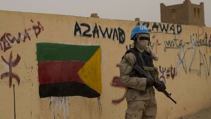 Un soldat des Nations unies garde l'entr&eacute;e d'un bureau de vote couverte de tags et d'un drapeau s&eacute;paratiste, le 28 juillet 2013,&nbsp;&agrave; Kidal (Mali). (REBECCA BLACKWELL/AP/SIPA / AP)