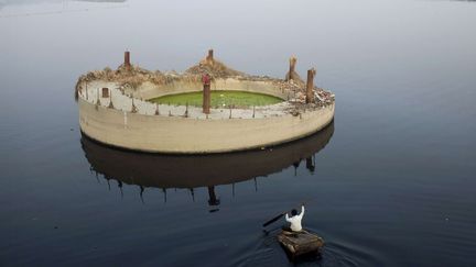 Un homme pagaie vers un &icirc;lot de b&eacute;ton, vestige de la construction d'un pont abandonn&eacute; sur la rivi&egrave;re Yamuna (Inde), le 6 f&eacute;vrier 2012. (KEVIN FRAYER / AP)