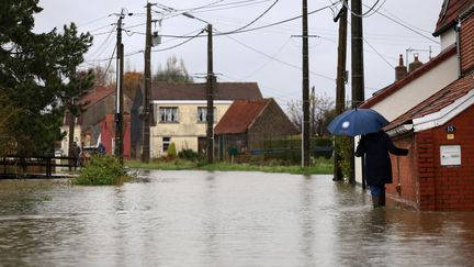 Une femme marche dans une rue inondée au Doulac, près de Saint-Omer (Pas-de-Calais), le 14 novembre 2023. (AURELIEN MORISSARD / POOL)