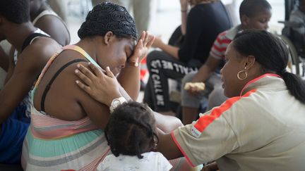 Une membre de la Croix-Rouge réconforte une sinistrée de Saint-Martin, le 9 septembre 2017, à l'aéroport de Pointe-à-Pitre, en Guadeloupe. (HELENE VALENZUELA / AFP)