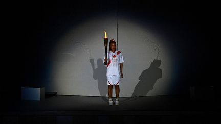 La joueuse de tennis japonaise Naomi Osaka porte la flamme olympique lors de l'ouverture des JO de Tokyo, le 23 juillet 2021. (DYLAN MARTINEZ / AFP)