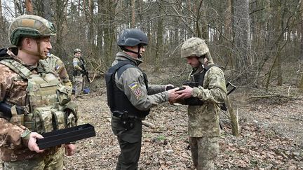 Le ministre ukrainien Oleksii Reznikov remet des armes à un militaire.  (STR / UKRAINIAN DEFENCE MINISTRY PRESS / AFP)