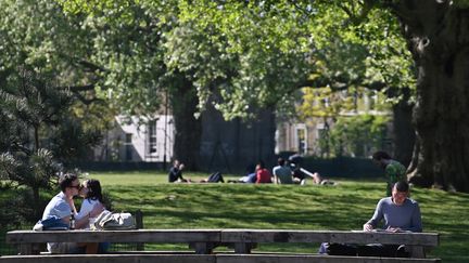 Un couple s'embrasse sur un banc dans un parc de Londres, le 25 avril 2020. (JUSTIN TALLIS / AFP)