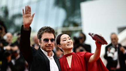 Le Français Jean-Michel Jarre, pionnier des musiques électroniques, en compagnie de son épouse, la star du cinéma chinois Gong Li, salue la foule sur le tapis rouge jeudi 18 mai au soir. (LOIC VENANCE / AFP)