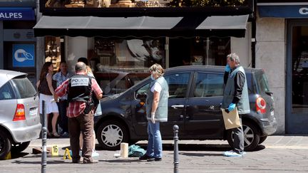 Des policiers enqu&ecirc;tent sur les lieux d'un braquage, vendredi 10 ao&ucirc;t &agrave; Grenoble (Is&egrave;re). (JEAN-PIERRE CLATOT / AFP)