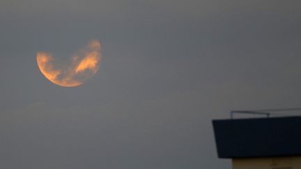 Privée des rayons du Soleil, la Lune s'assombrit et prend une teinte brique car l'atmosphère terrestre dévie les rayons rouges de la lumière solaire vers l'intérieur du cône d'ombre. La Lune peut alors les renvoyer, comme ici à Netanya (Israël). (JACK GUEZ / AFP)