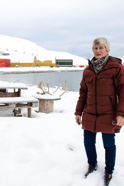 Rebekka Nordtømme pose dans son jardin au bord du fjord de Longyearbyen, le 28 mars 2018. A l'arrière-plan, la cheminée de la centrale à charbon de la ville. (YANN THOMPSON / FRANCEINFO)