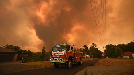 Un camion de pompier stationne sur une route alors qu'un feu brûle à Bargo, au sud-ouest de Sydney, le 21 décembre.&nbsp;Au moins 3 millions d'hectares ont brûlé à travers le pays ces derniers mois dans des incendies qui ont causé la mort de 10 personnes et détruit plus de 800 maisons.&nbsp; (PETER PARKS / AFP)