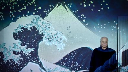 Le collectionneur&nbsp;Georges Leskowicz pose devant une projection de l'Envers de la grande vague de Kanagawa d'Hokusai (1760-1849) à Aix-en-Provence, le 6 novembre 2019 (GERARD JULIEN / AFP)