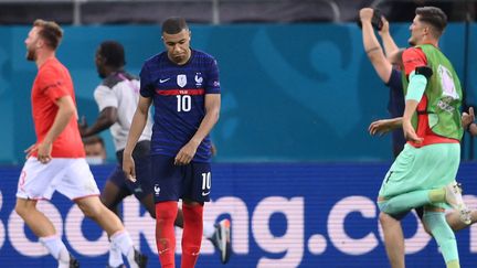 Toute la déception de Kylian Mbappé après son tir au but manqué face à la Suisse, le 28 juin 2021. Le joueur du PSG a vu sa frappe repoussée par Yann Sommer et précipite l'élimination des Bleus. Derrière, les Suisses se ruent vers leur héros du soir et célèbrent leur premier quart de finale en compétition internationale depuis... 1938 ! (FRANCK FIFE / AFP)