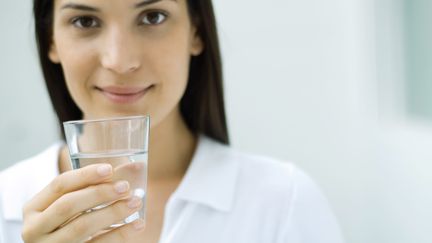 Une jeune femme tient un verre d'eau. (ERIC AUDRAS / MAXPPP)