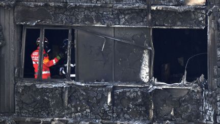 Des pompiers et des policiers inspectent l'intérieur de la tour Grenfell, le 16 juin 2017, à Londres. (CHRIS J RATCLIFFE / AFP)