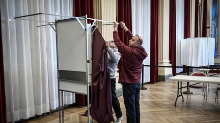 Des employés de la mairie installent un isoloir dans le bureau de vote de la mairie du 10e arrondissement de Paris, à Paris, le 8 avril 2022. (STEPHANE DE SAKUTIN / AFP)