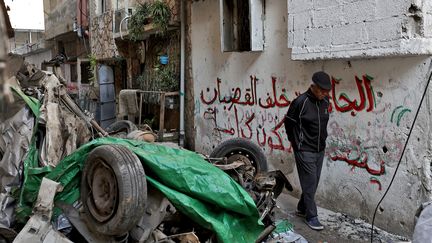 A man walks past a car destroyed by Israeli bombing on January 9, 2024, in the occupied West Bank.  (ZAIN JAAFAR / AFP)