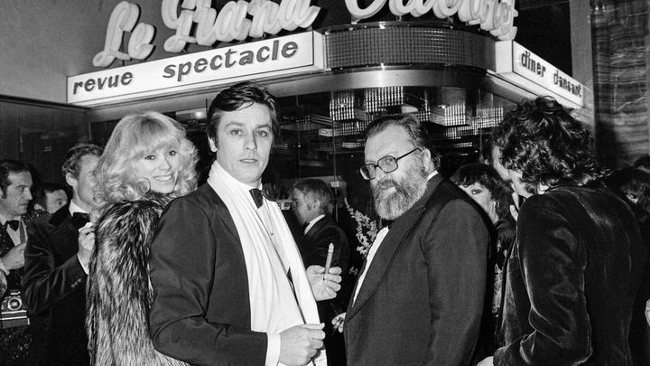 Alain Delon et Mireille Darc, en couple, et le réalisateur italien Sergio Leone, lors de l'ouverture de la discothèque "Le Grand Cabaret", le 15 janvier 1977 à Nice (Alpes-Maritimes). (AFP)