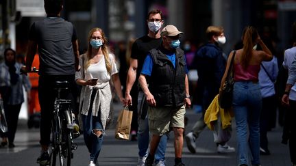 Des passants portant des masques marchent dans les rues. (JOHN THYS / AFP)