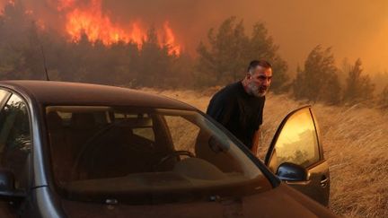 Un automobiliste tente de fuir les flammes à Dion, près d'Athènes (Grèce), le 12 août 2024.