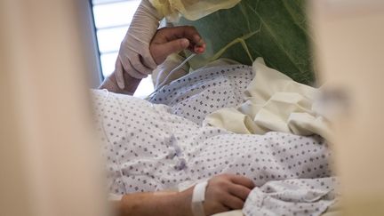 Une infirmière s'occupe d'une&nbsp;personne atteinte du Covid-19, à&nbsp;l'hôpital (illustration). (LOIC VENANCE / AFP)