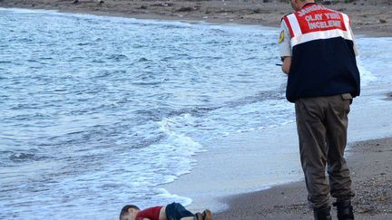 En moins de vingt-quatre heures, la photo est devenue virale, partagée dans le monde entier. Elle montre le corps sans vie d'un petit enfant syrien gisant sur une plage de Bodrum, en Turquie. Face contre terre, le petit Aylan, 3 ans, a été retrouvé par les autorités turques, mercredi 2 septembre, non loin de deux autres corps : ceux de Galip, son frère de 5 ans, et de sa mère, Rehan. Seul Abdullah, son père, a été retrouvé vivant.  (NILUFER DEMIR / DOGAN NEWS AGENCY / AFP)