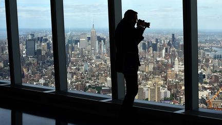 Un homme filme la vue depuis le 102e &eacute;tage du nouveau World Trade Center, mercredi 20 mai 2015, &agrave; New York (Etats-Unis).&nbsp; (TIMOTHY A. CLARY / AFP)