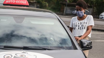 Une femme s'apprête à prendre le volant d'un véhicule d'auto-école, début juin, à&nbsp;Mamoudzou (Mayotte). (ALI AL-DAHER / AFP)