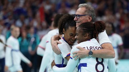 Olivier Krumbholz enlacé par Estelle Nze Minko et Coralie Lassource après la victoire des Bleues en demi-finales du tournoi olympique contre la Suède, le 8 août 2024 à Villeneuve-d'Ascq (Nord). (THOMAS COEX / AFP)