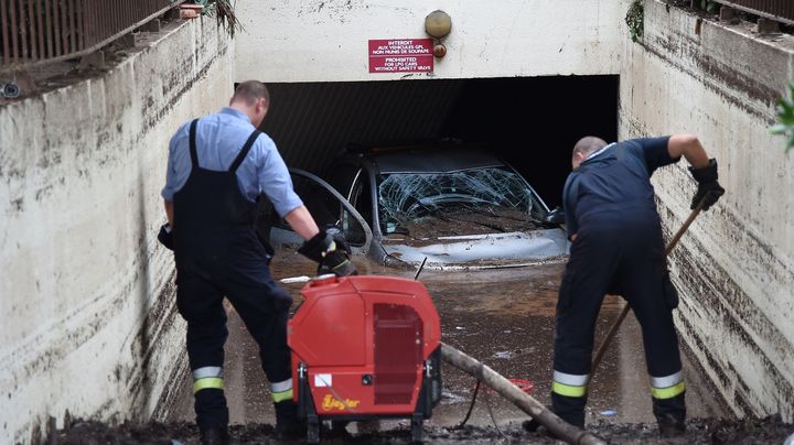 Des habitants nettoient l'entr&eacute;e d'un parking souterrain &agrave;&nbsp;Mandelieu-la-Napoule (Alpes-Maritimes), apr&egrave;s les orages meurtriers, le 5 octobre 2015. (ANNE-CHRISTINE POUJOULAT / AFP)