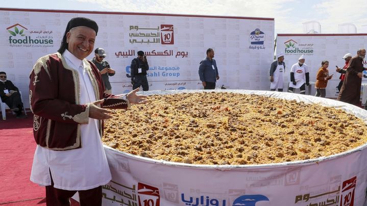 Les gens se rassemblent autour d'un couscous géant préparé par des chefs libyens sur le site de l'ancien théâtre romain de Sabratha, à environ 70 km à l'ouest de la capitale Tripoli, le 10 mars 2023. (MAHMUD TURKIA / AFP)