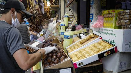 Un vendeur prépare une boîte de dattes à l'extérieur d'une épicerie dans le 18e arrondissement de Paris, le 24 avril 2020, au premier jour du ramadan. (GEOFFROY VAN DER HASSELT / AFP)