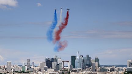 La Patrouille de France vole au-dessus des Champs-Elysées, à Paris, le 14 juillet 2016, avec, au loin, vue sur la Défense. (STEPHANE DE SAKUTIN / AFP)