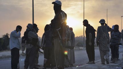 Des combattants de l'Etat islamique en Irak et au Levant montent la garde &agrave; un poste de contr&ocirc;le, le 11 juin 2014, &agrave; Mossoul (Irak). (REUTERS)