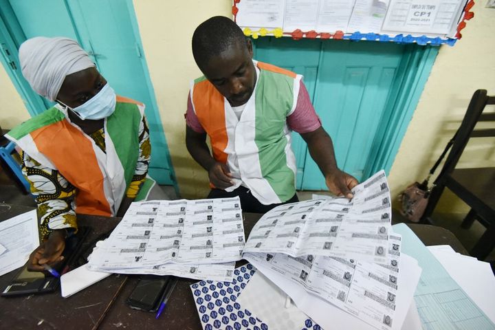 Des membres de la Commission électorale indépendante décomptent les voix obtenues par les candidats dans un bureau de Yopougon dans la banlieue d'Abidjan le 6 mars 2021. (SIA KAMBOU / AFP)