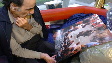 Mehran Karimi Nasseri, le réfugié de Roissy, regarde l'affiche du Terminal, le film de Steven Spielberg qu'il a inspiré, le 12 août 2004 (STEPHANE DE SAKUTIN / AFP)