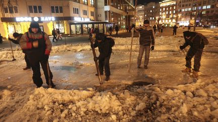 Des opposants au gouvernement repoussent la neige pour &eacute;riger une&nbsp;barricade dans une rue de Kiev, en Ukraine, le 29 janvier 2014. (KONSTANTIN CHERNICHKIN / REUTERS)