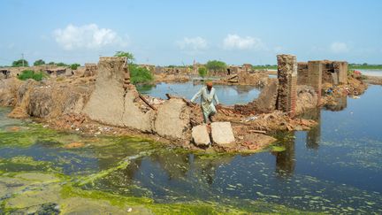 Un homme traverse ce qu'il reste de sa maison détruite par les pluies de mousson dans la province du Balouchistan (Pakistan), le 28 août 2022. (FIDA HUSSAIN / AFP)