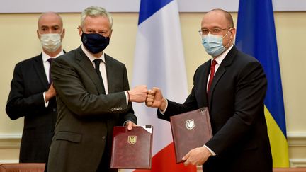 Le Premier ministre ukrainien Denys Shmyhal (à droite) et Bruno Le Maire, ministre français de l'Économie et des Finances (à gauche) signent des accords pour 1,3 milliard d'euros, à Kiev (Ukraine), le 13 mai 2021. (SERGEI SUPINSKY / AFP)