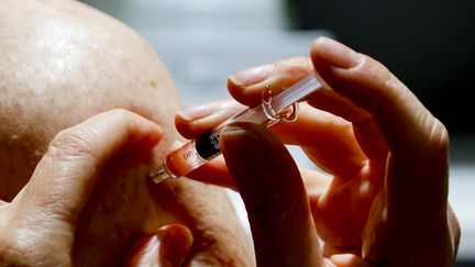 Une patiente se fait vacciner contre la grippe saisonnière dans une pharmacie, à Paris, le 13 octobre 2020. (LUDOVIC MARIN / AFP)