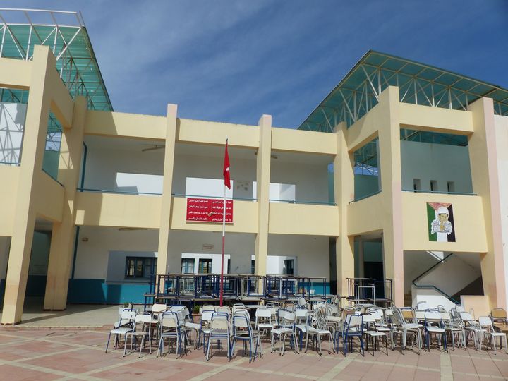 La cour du lycée du quartier&nbsp;Elnasr II, le 13 octobre 2019, centre de vote pour le 2e tour de la présidentielle. A droite, la peinture représentant l'enfant palestinien Mohamed Al-Dura, mort en septembre 2000. Au-dessus du podium et du drapeau, une inscription avec certaines des strophes de l'hymne national tunisien. (FTV - Laurent Ribadeau Dumas)