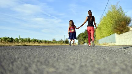 Une petite fille tenant la main de sa maman (illustration). (LOIC VENANCE / AFP)