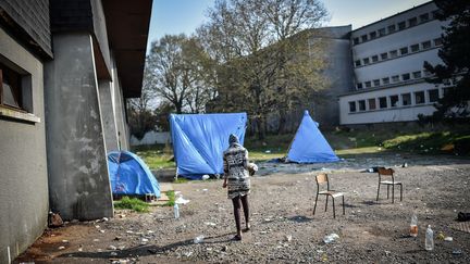 Une femme marche devant un gymnase occupé par des migrants dans l'ancien lycée Jeanne-Bernard de Saint-Herblain (Loire-Atlantique), le 28 mars 2019. (LOIC VENANCE / AFP)