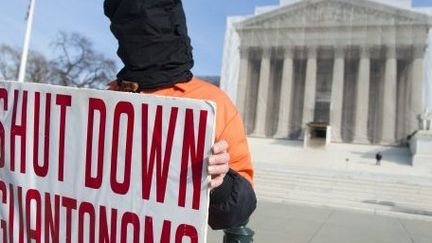 Un manifestant en tenue orange, celle des prisonniers de Guantanamo, proteste devant la Cour suprême américaine, à Washington, le 8 Janvier 2013, contre la détention illégale de prisonniers dans le camp américain. (AFP PHOTO / SAUL LOEB)