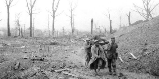 Durant la bataille du Chemin des Dames, en avril 1917, quatre militaires, dont un prisonnier allemand, portent un brancard avec un blessé à travers un paysage dévasté par la guerre. (AFP - Frantz Adam)