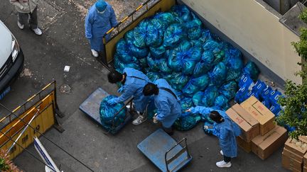 Des livreurs en tenue de protection délivrent les paniers de vivres de la semaine aux habitants de Shanghaï confinés en raison du Covid-19, le 16 avril 2022. (HECTOR RETAMAL / AFP)