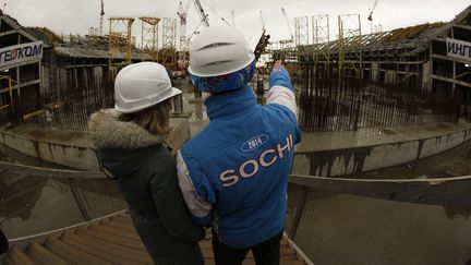 Un ouvrier montre le chantier du stade olympique de Sotchi, en Russie, &agrave; une journaliste, le 10 f&eacute;vrier 2012. Le stade doit accueillir les JO d'hiver en 2014, puis le Mondial 2018 de football. (WOLFGANG RATAY / REUTERS)