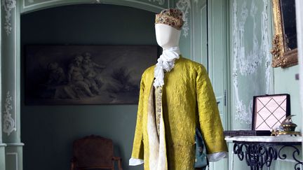 Robe de chambre en Banyan, en satin vert jaune brodé au cordon de motifs géométriques avec une doublure en coton écru. Veste sans manche et droguet de soie façonné de fleurs vert, jaune et crème, avec des boutons lamés et cannetillés sur feuille de cuivre. 
 (Gilles Martin-Raget)