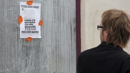 Un homme regarde une affichette contre le projet d'apéro géant à La Goutte d'or, le 15/06/2010 (AFP/Bertrand Langlois)