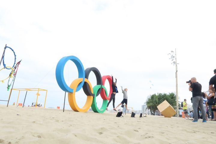 Des touristes posent devant les anneaux olympiques installés sur la plage de Copacabana, à Rio de Janeiro (Brésil), le 3 août 2016. (PIERRE GODON / FRANCETV INFO)